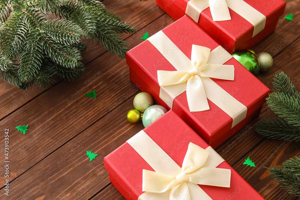 Beautiful composition with Christmas gift boxes, fir branches and balls on wooden background