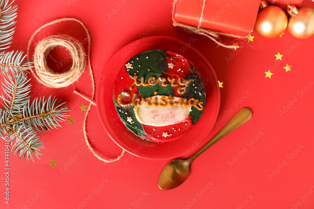 Plate with tasty bento cake and Christmas decor on red background