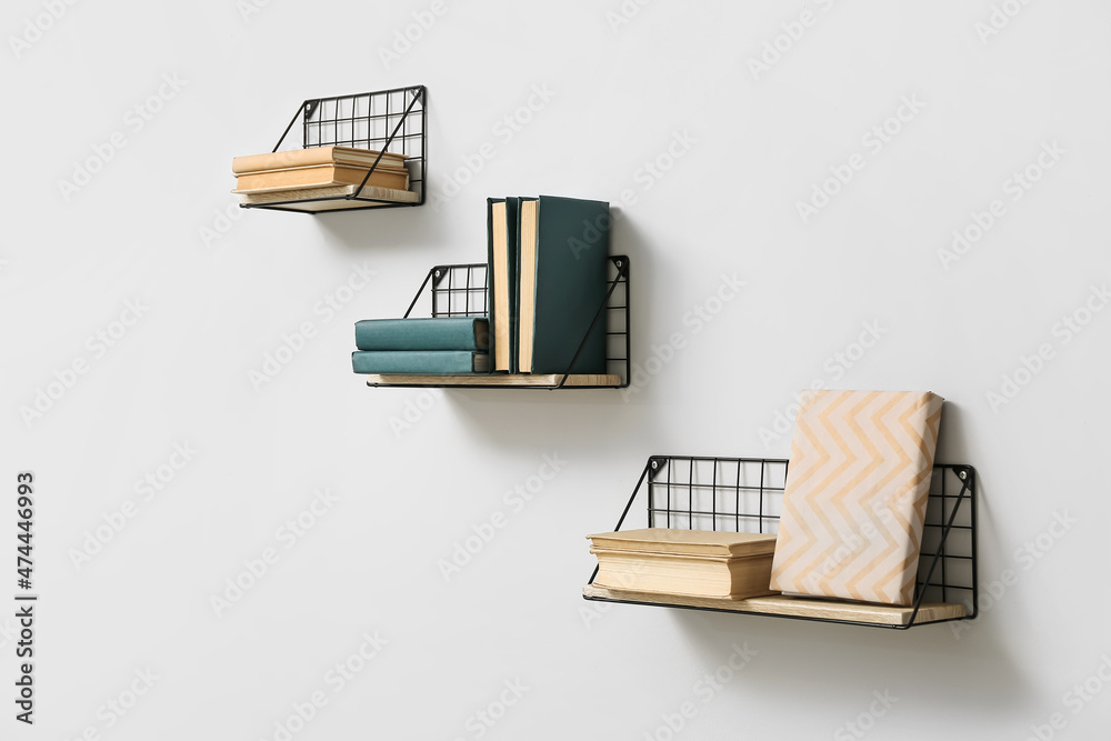 Modern shelves with books hanging on light wall