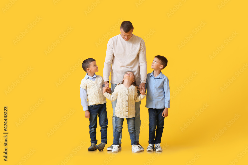 Portrait of father with little children on yellow background