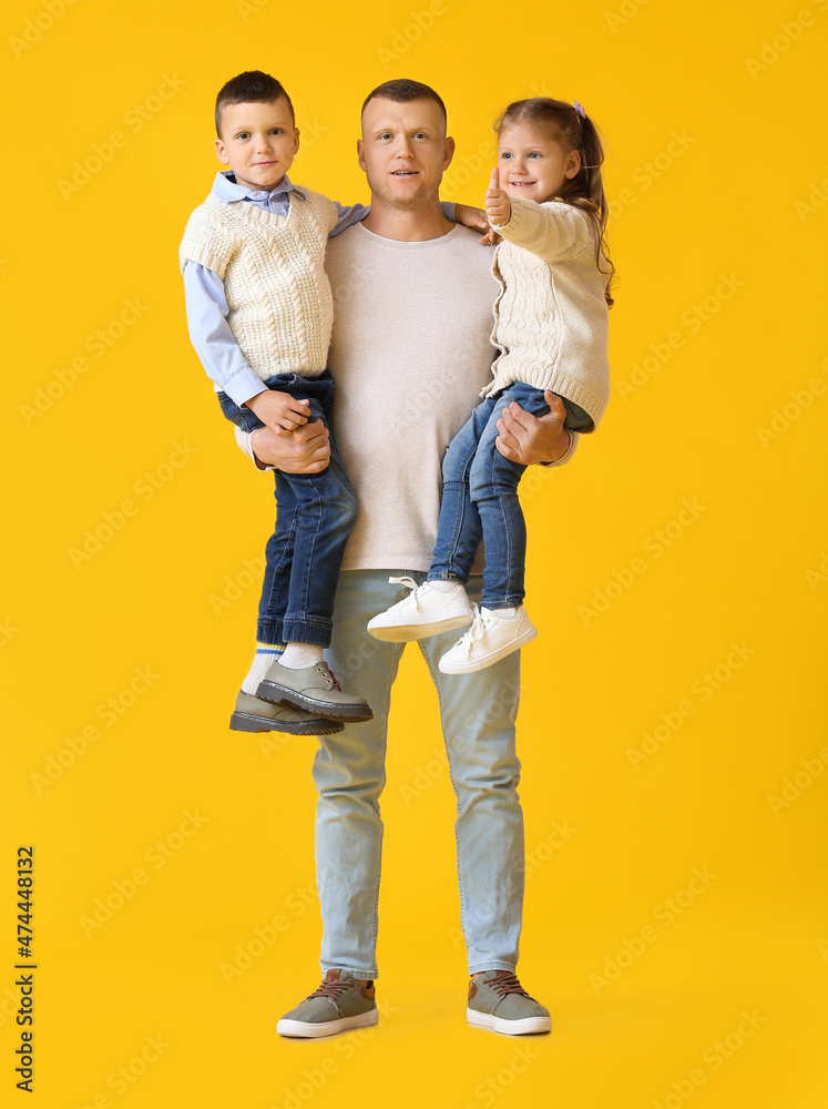 Portrait of father with little children on yellow background