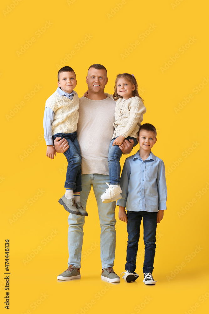 Portrait of father with little children on yellow background