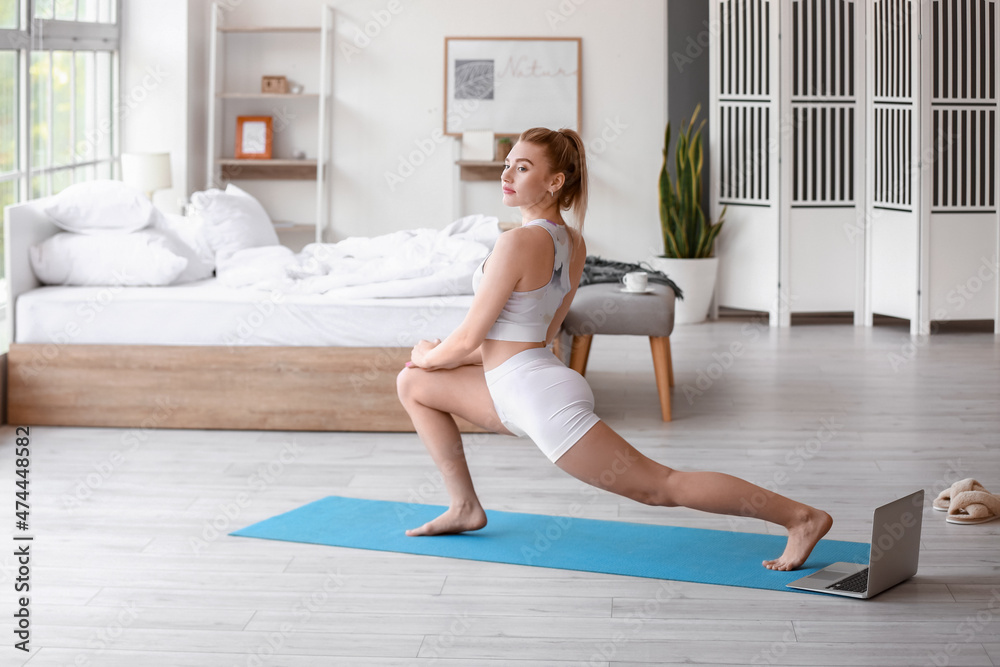 Pretty young woman practicing yoga at home in morning