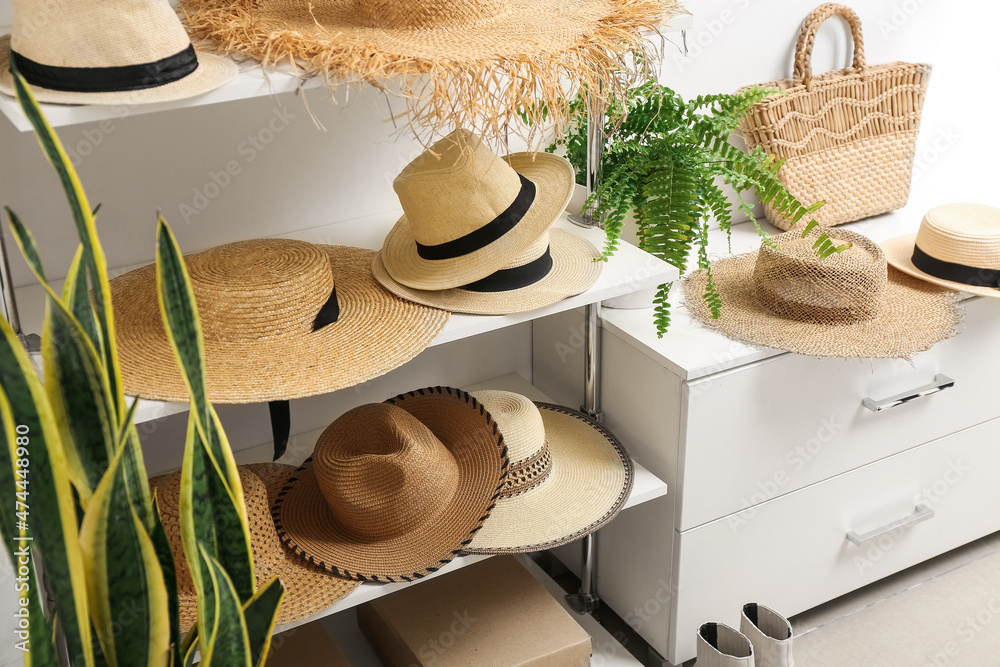 Trendy straw hats on shelves in wardrobe