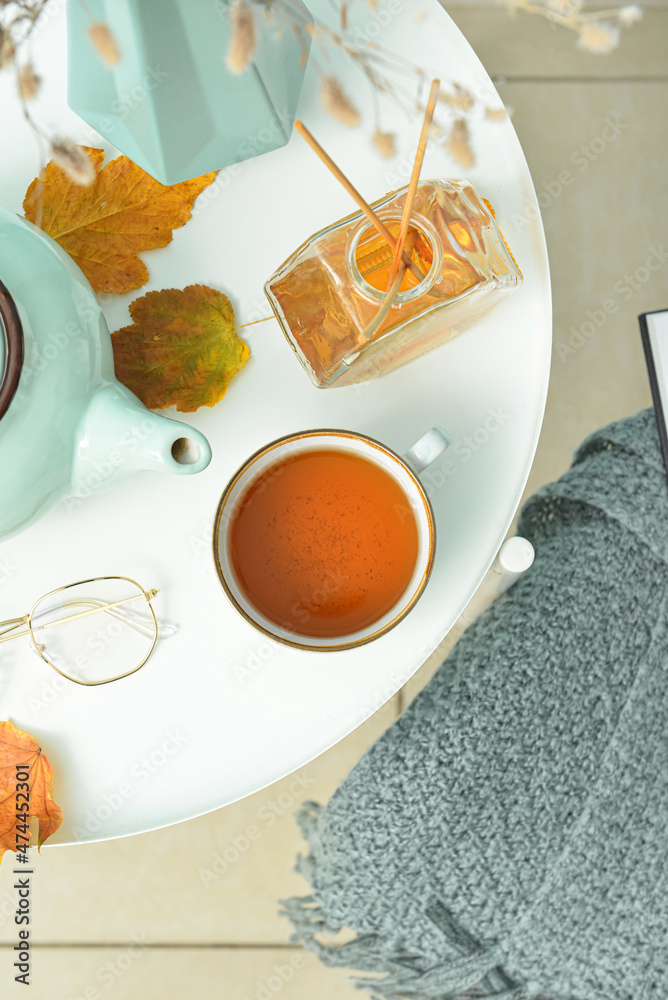 Cup of hot tea and reed diffuser on table in room