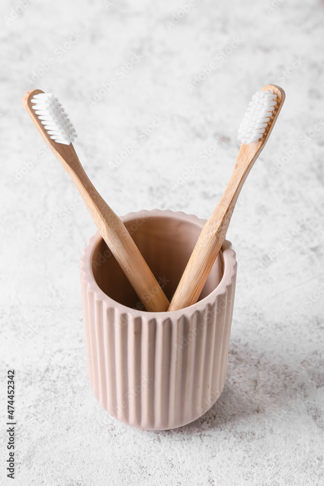 Holder with wooden toothbrushes on light background