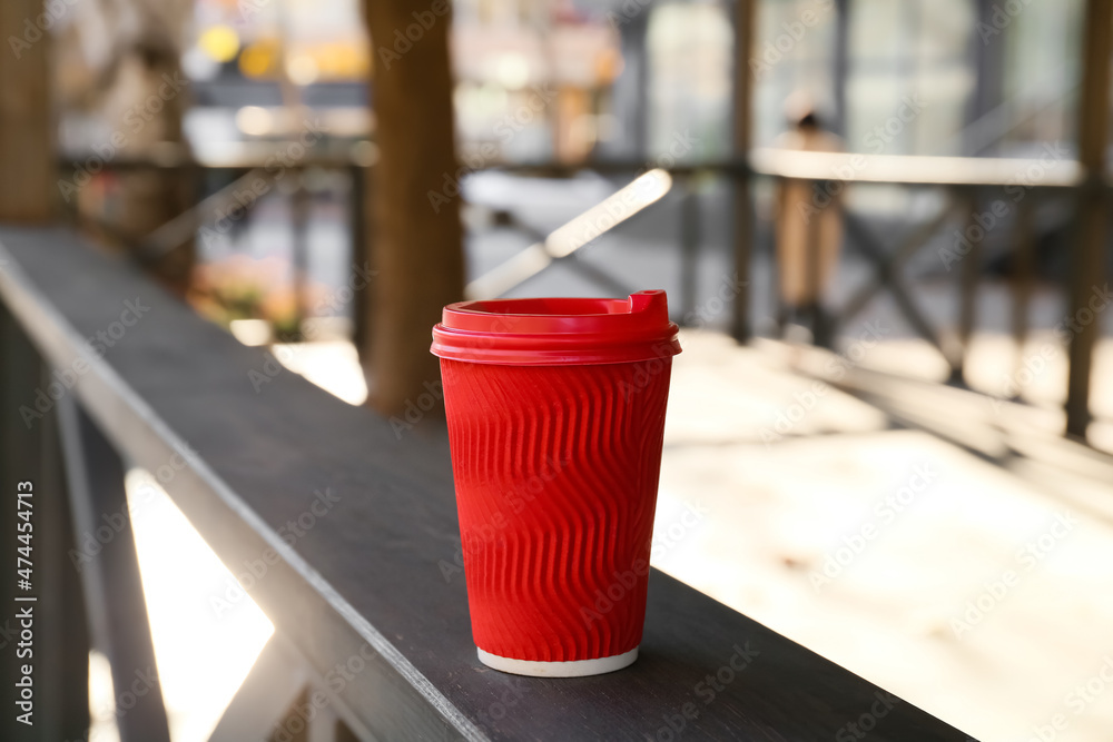 Takeaway cup of delicious latte on fence outdoors