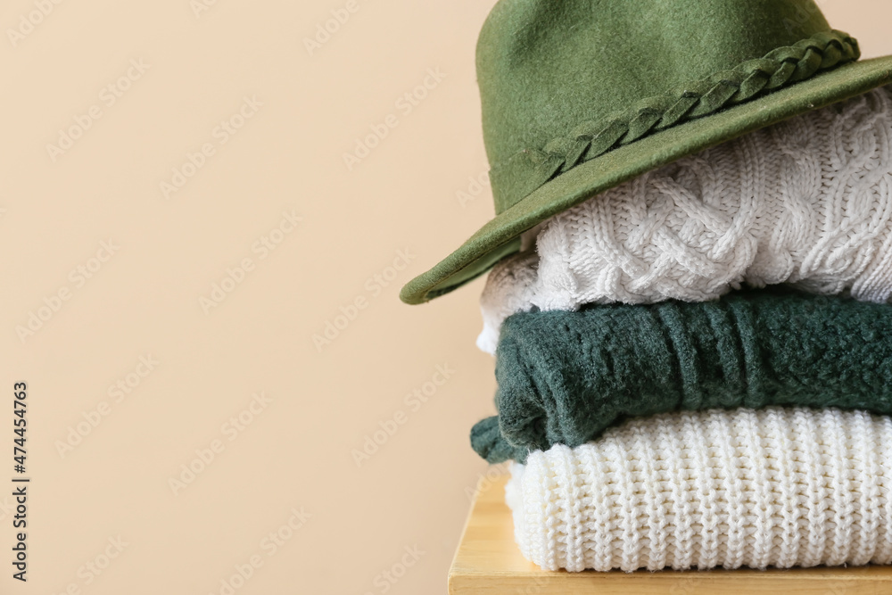 Stylish winter clothes on stool against light background