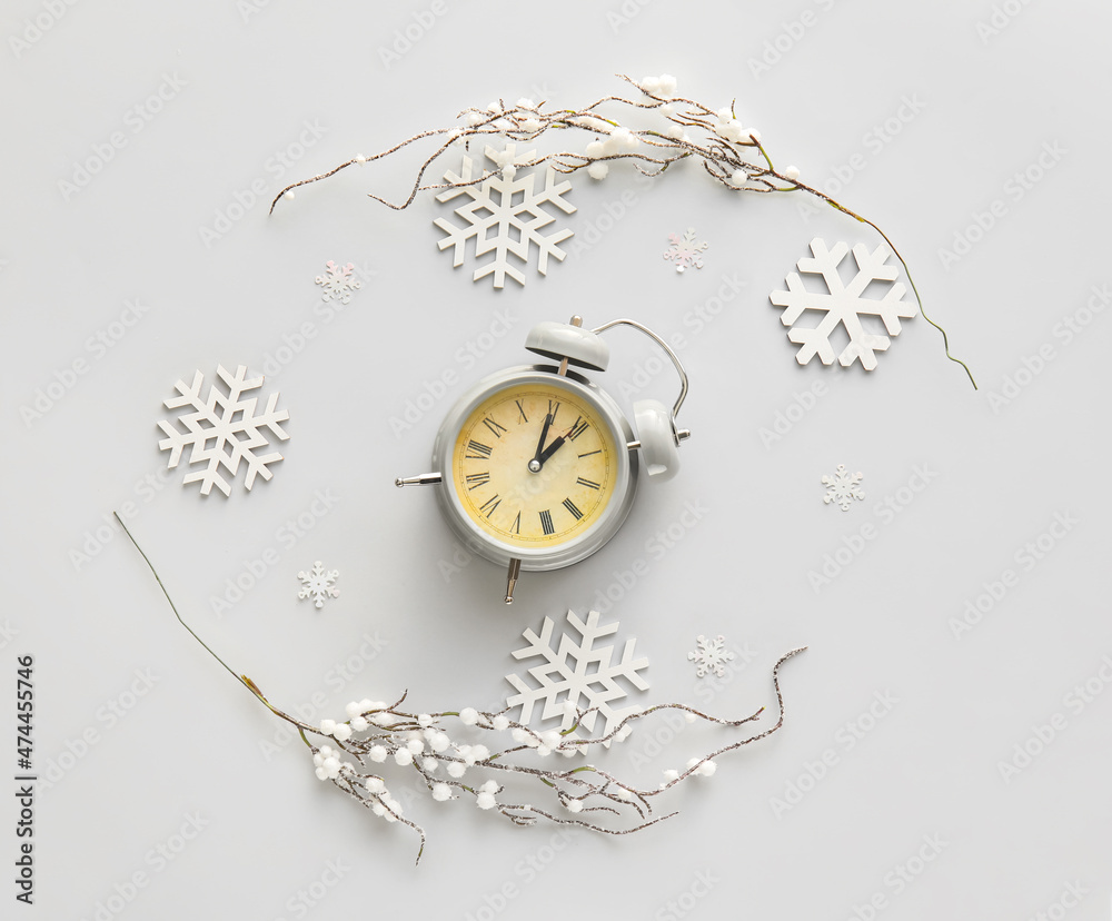 Stylish alarm clock and Christmas decor on light background