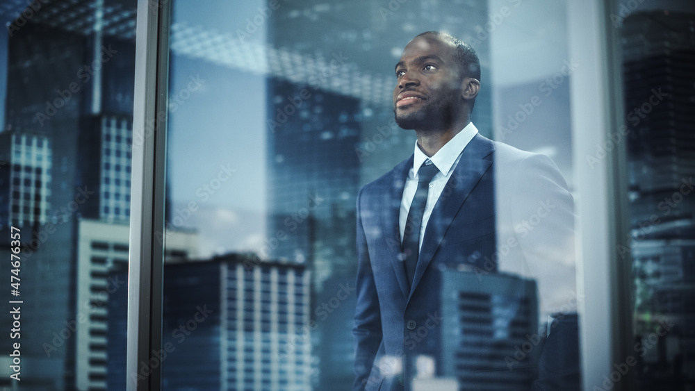 Thoughtful African-American Businessman in a Perfect Tailored Suit Standing in His Office Looking ou