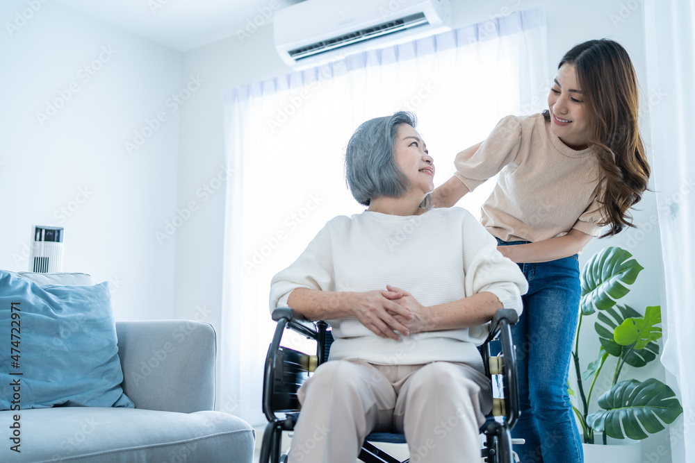 Asian young daughter support old disabled woman on wheelchair at home. 