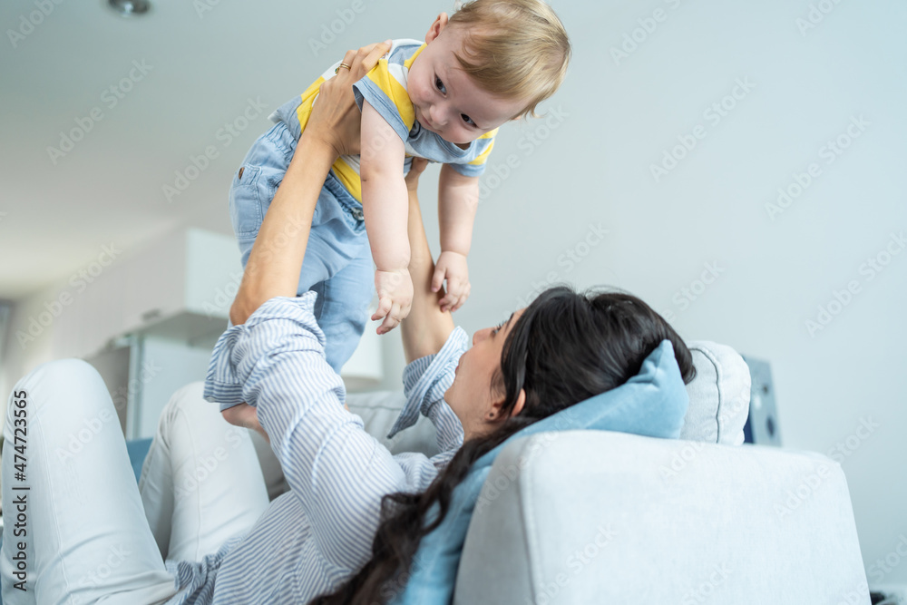 爱高加索的妈妈在客厅的沙发上和男婴玩耍。