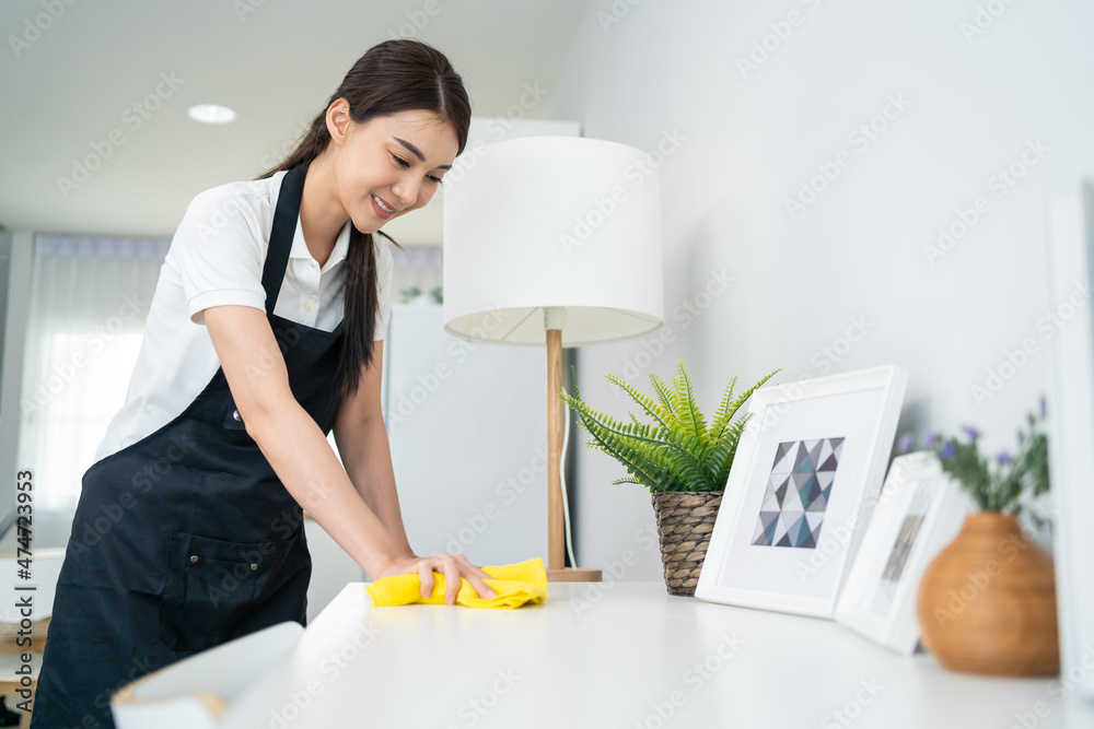 亚洲清洁服务女工在家里的客厅里打扫卫生。