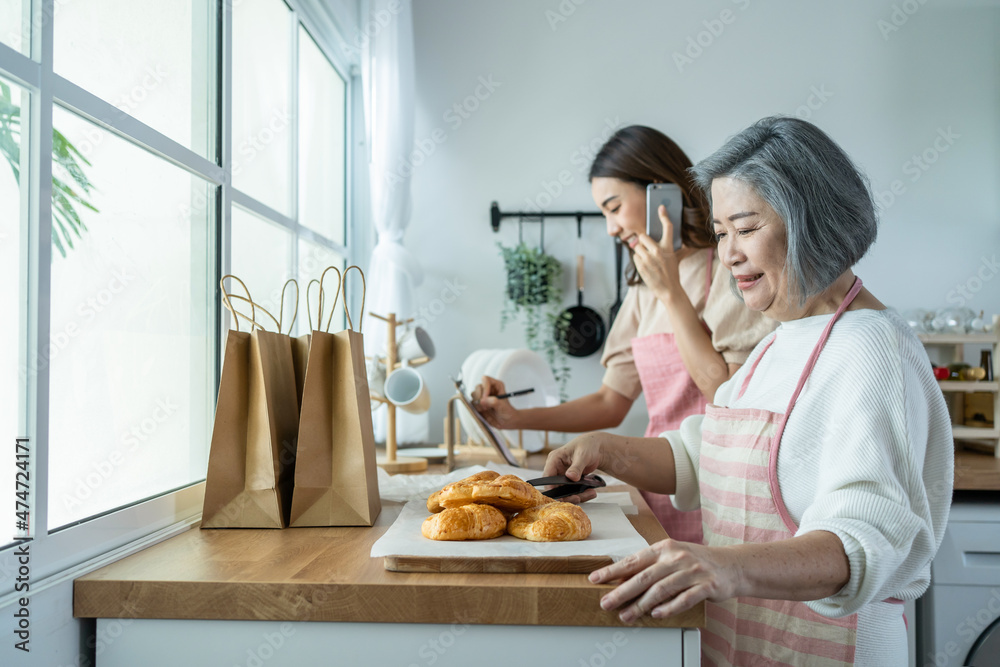 亚洲幸福家庭，资深妈妈和女儿在家做饭和销售