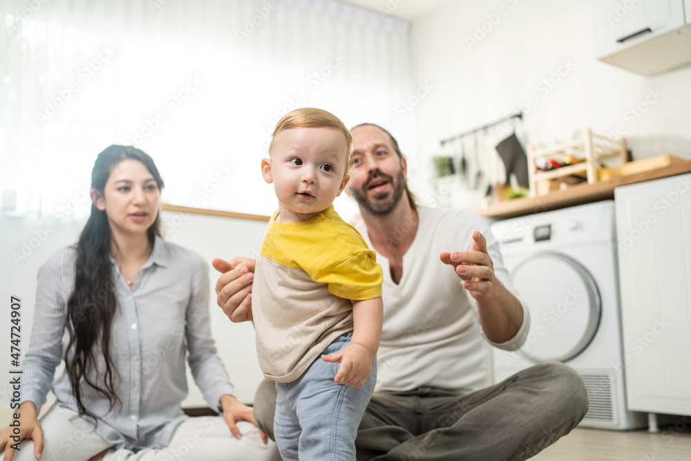 高加索男婴在父母的支持下学会走路。