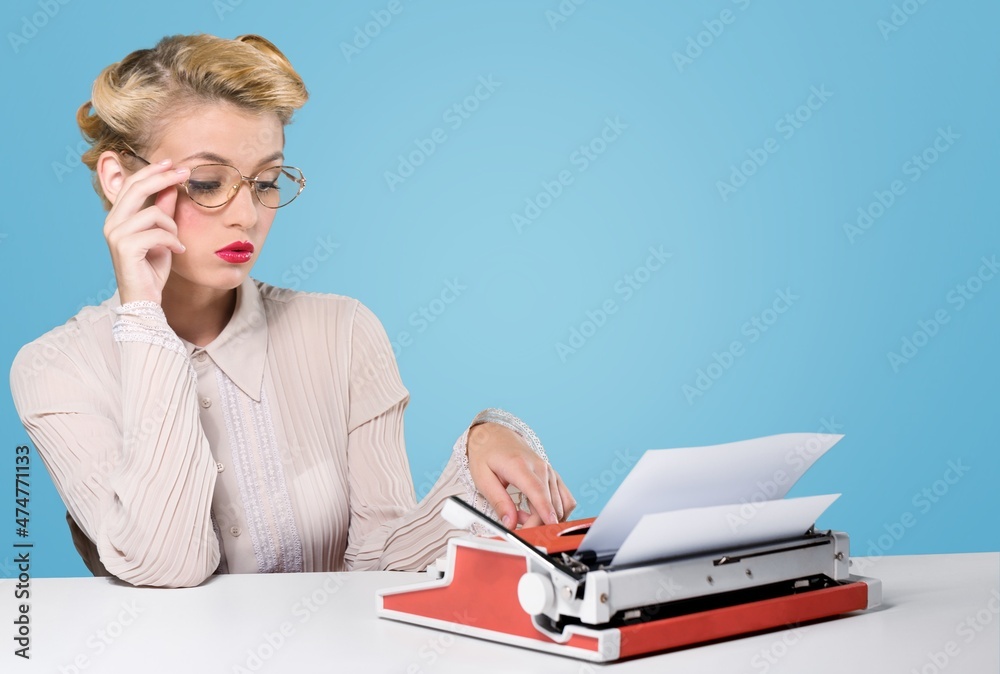 young woman writer at a typewriter, writing a text. Young at a table with a vintage typewrite