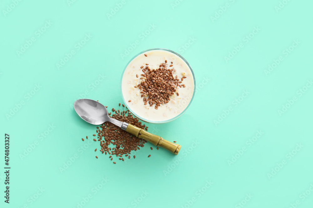 Tasty dessert with flax seeds and yoghurt in glass on color background