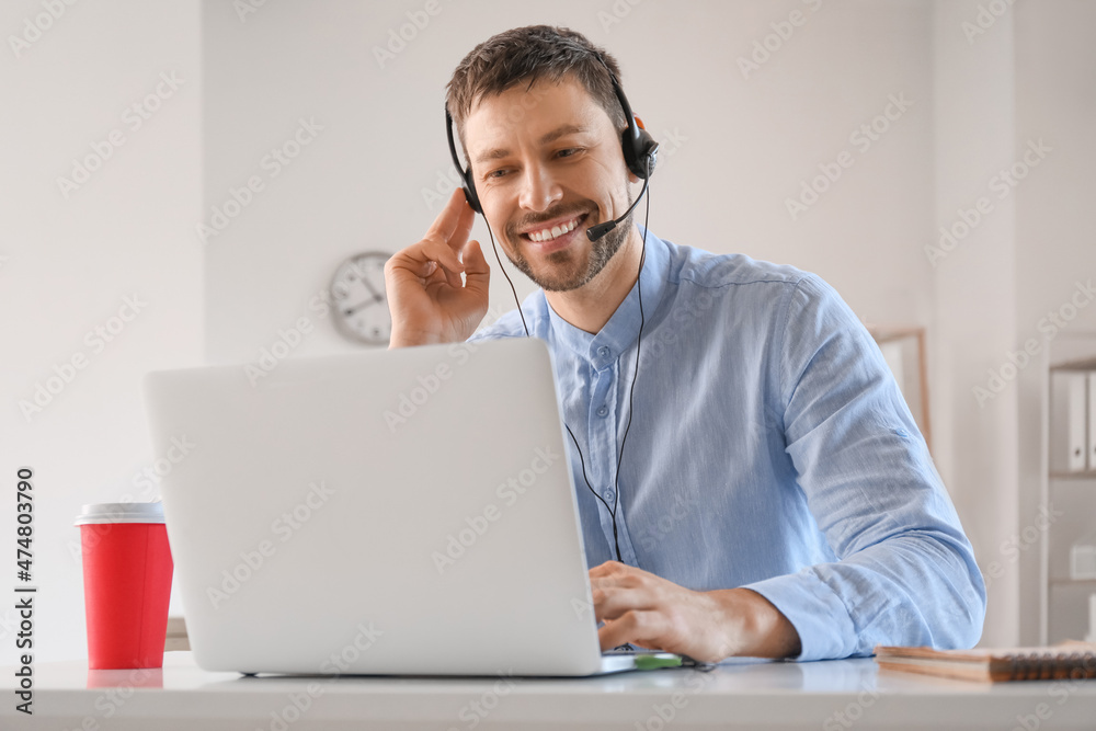 Consultant of call center working with laptop at table in office