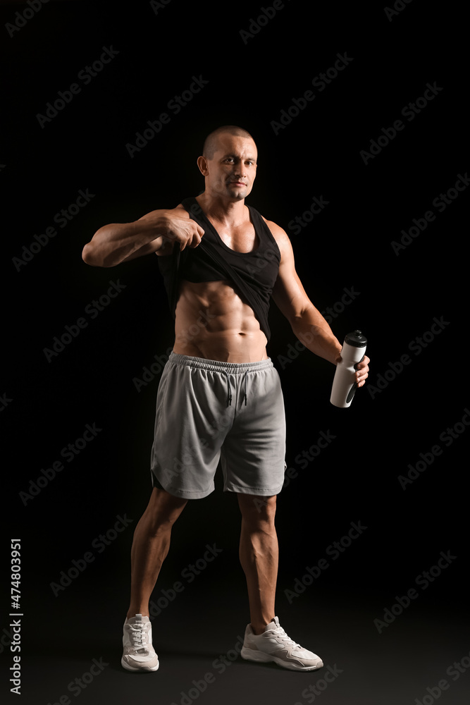 Male bodybuilder with protein shake on dark background