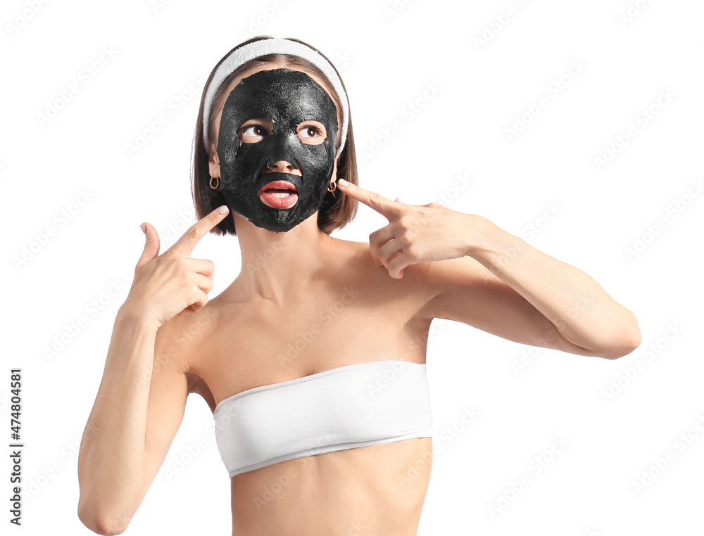 Young woman with activated charcoal mask on her face against white background