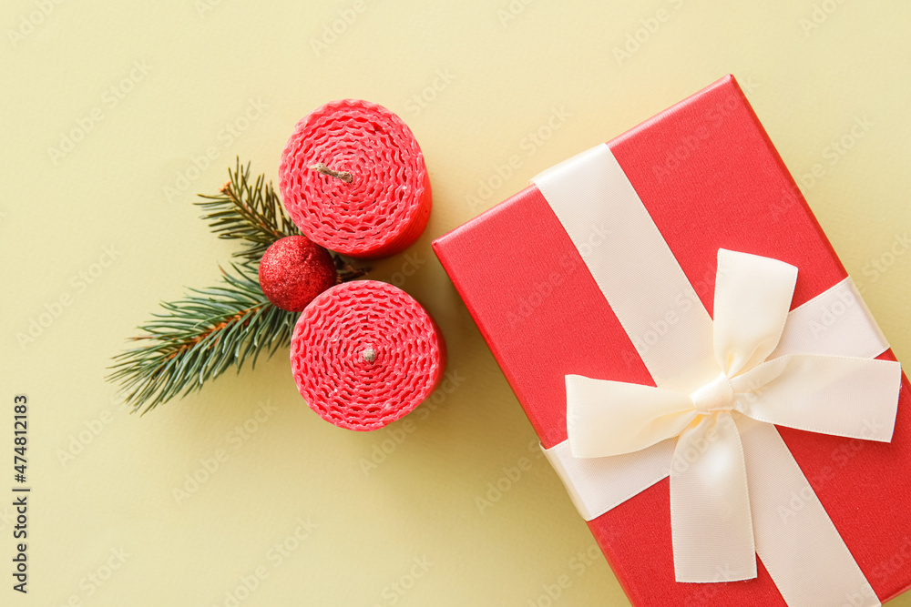 Composition with Christmas gift box, candles and fir branches on color background