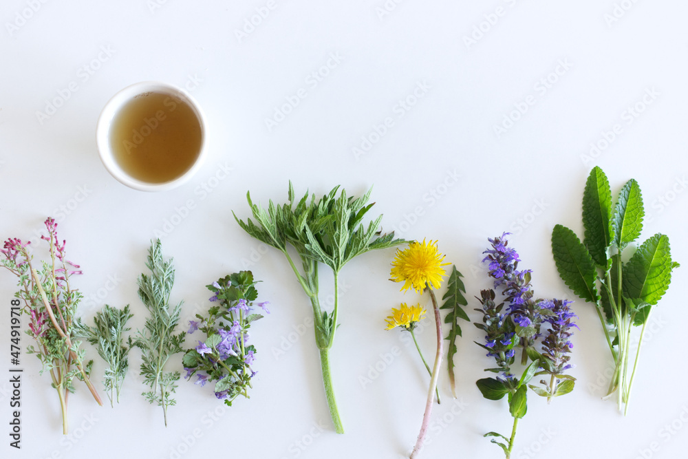 可食用的鲜花收藏和一杯白底隔离的茶。俯视图。