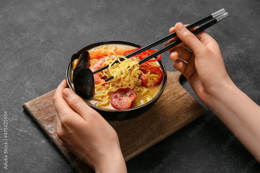 Woman eating tasty Thai soup from bowl