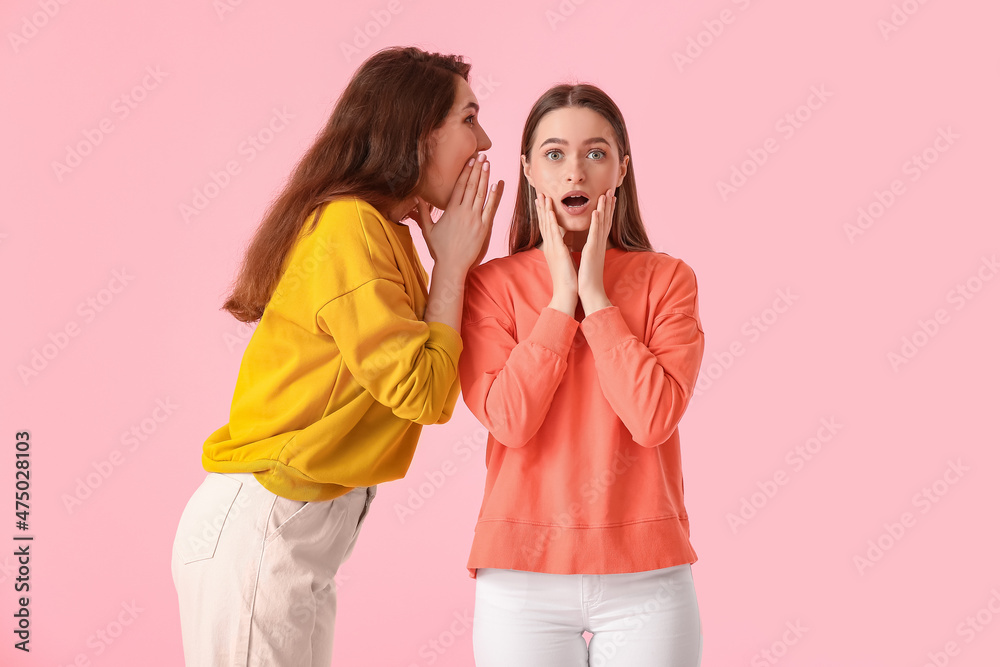 Young gossiping women on color background