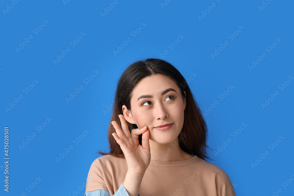 Young Asian woman zipping her mouth on color background