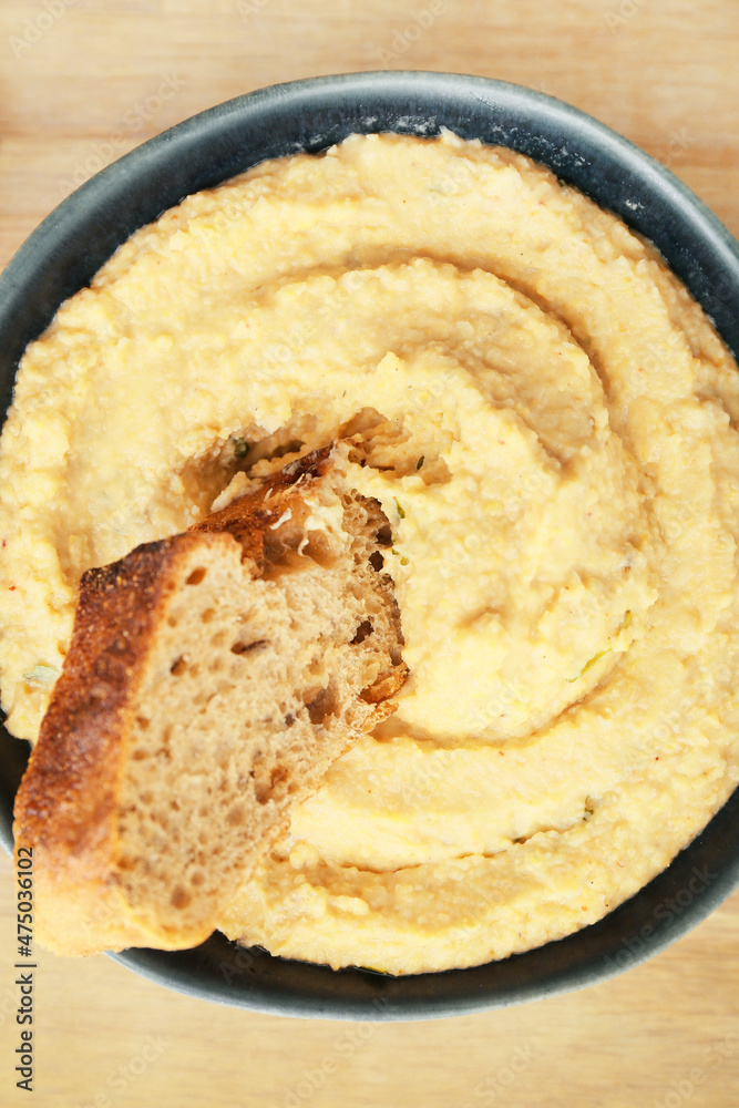 Bowl with delicious hummus and bread on table, closeup