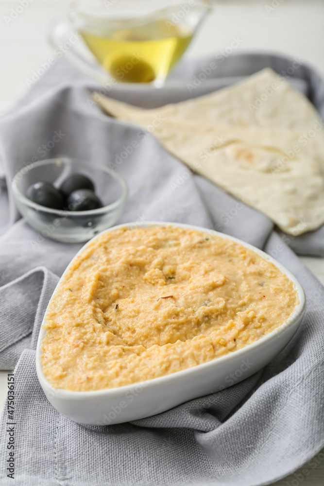 Bowl with delicious hummus on table, closeup