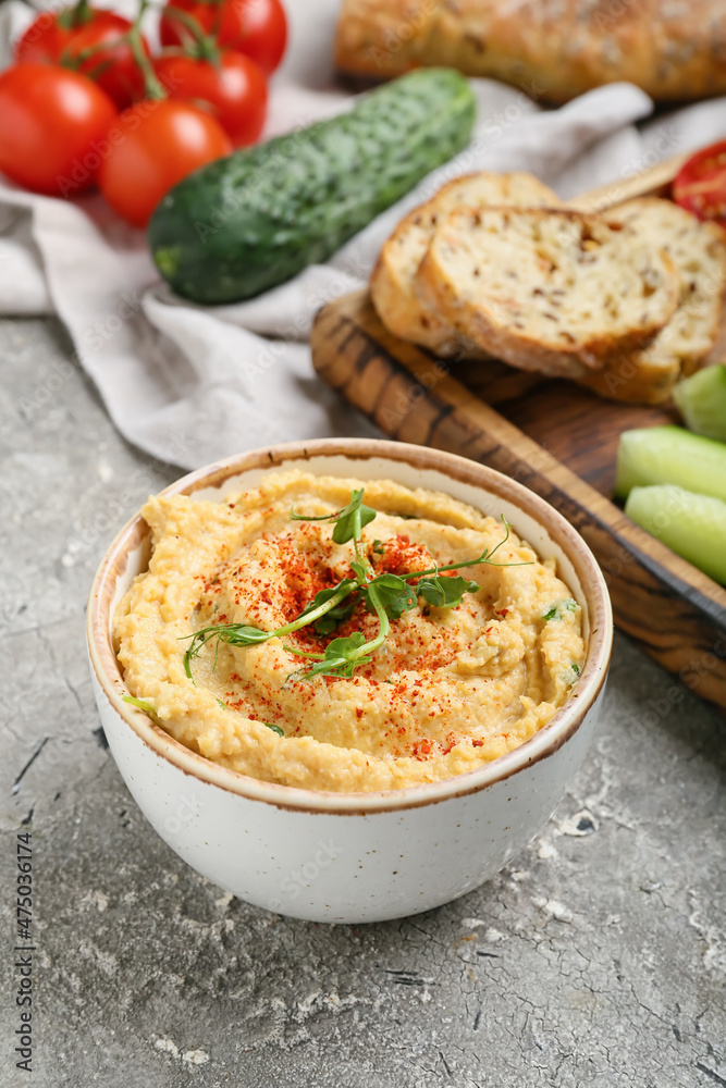 Bowl with delicious hummus on grey background, closeup