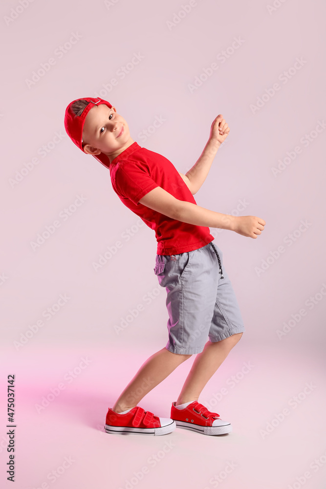 Cute little boy dancing on grey background