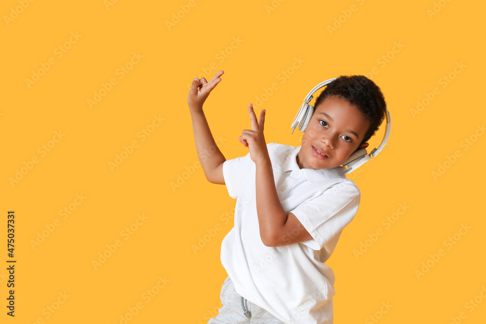 Dancing African-American boy listening to music on color background