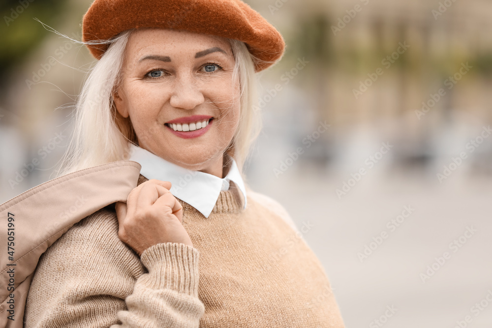 Portrait of mature woman in stylish beret hat on city street