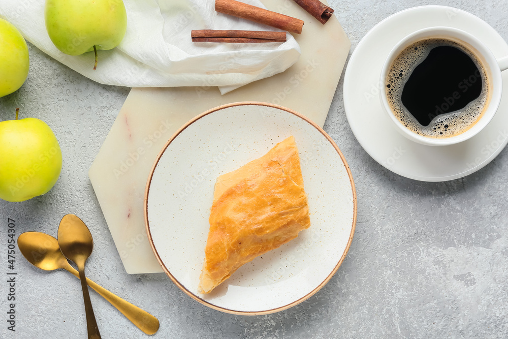 Plate with tasty apple strudel, cup of coffee and fruits on light background