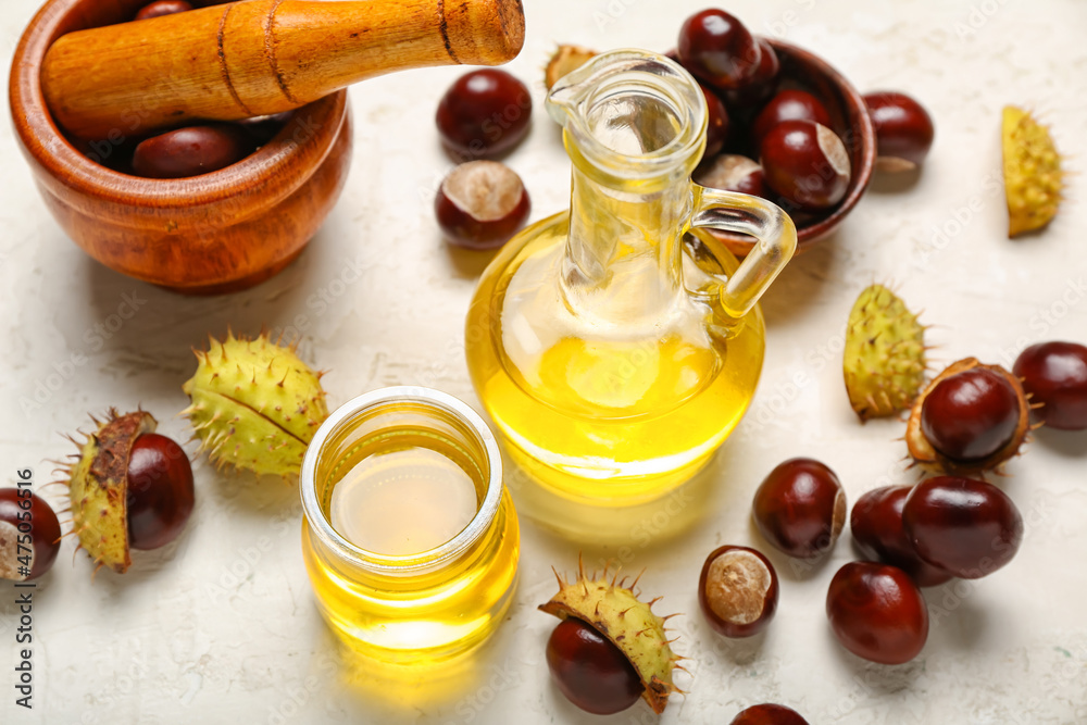 Composition with essential oil and fresh chestnuts on light background