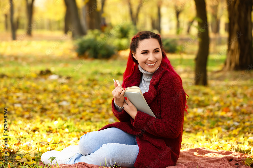 Beautiful woman with warm coat and book in autumn park