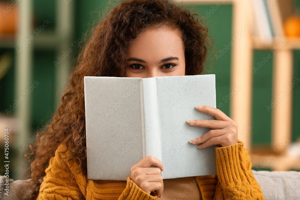 Young African-American woman with book at home