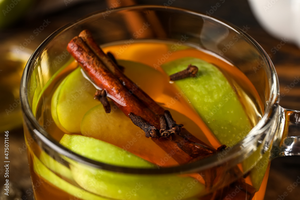 Glass cup of tasty fruit tea with cinnamon on wooden background, closeup