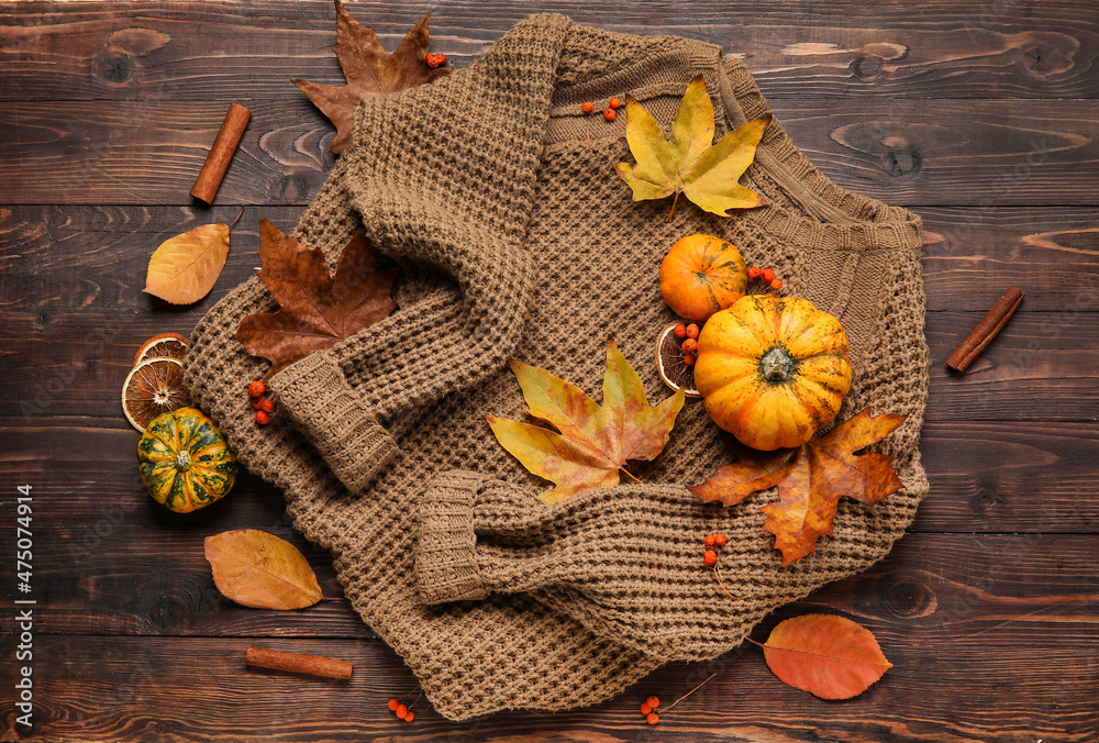 Trendy sweater and autumn decor on wooden background