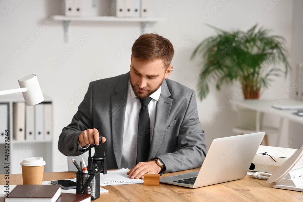 Male notary public attaching seal to document in office