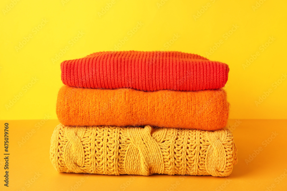 Stack of autumn clothes on color background