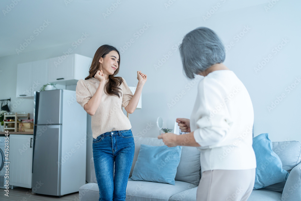 亚洲滑稽的老年母女在客厅里一起跳舞。