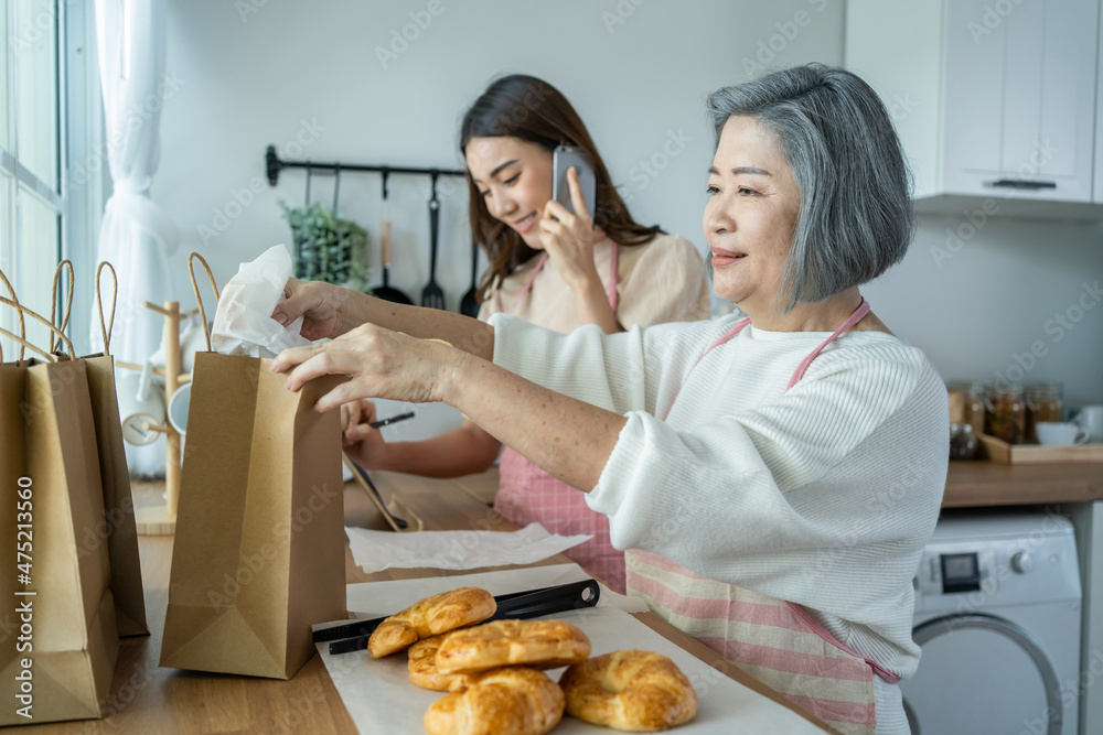 亚洲幸福家庭，资深妈妈和女儿在家做饭和销售