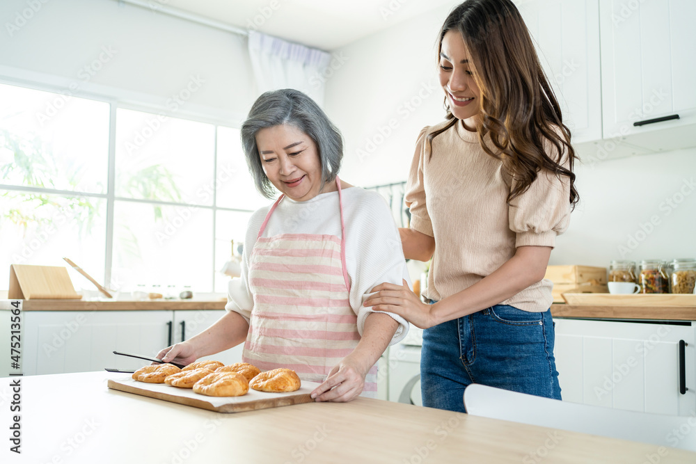 亚洲可爱的家庭，年幼的女儿看着年迈的母亲在厨房做饭