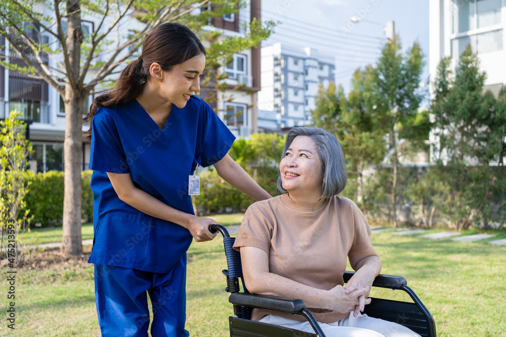 Asian happy senior woman patient sitting on wheelchair at green park.