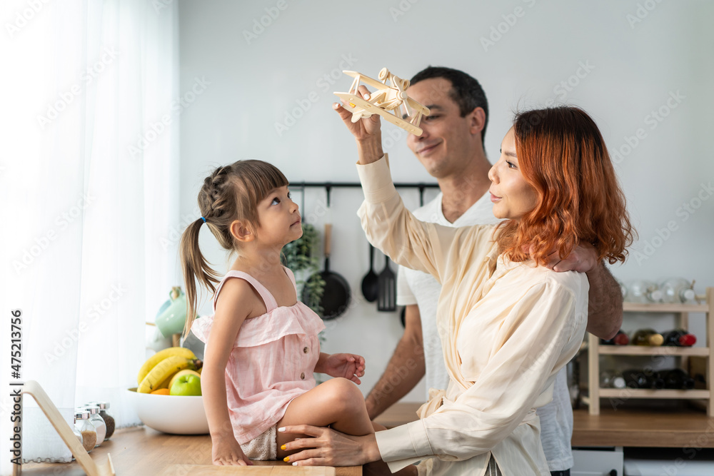 亚洲有魅力的父母在厨房里和孩子玩飞机玩具