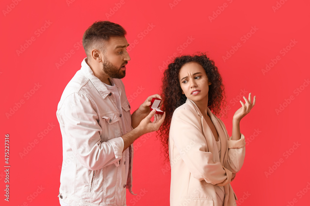 Young African-American woman rejecting marriage proposal on color background