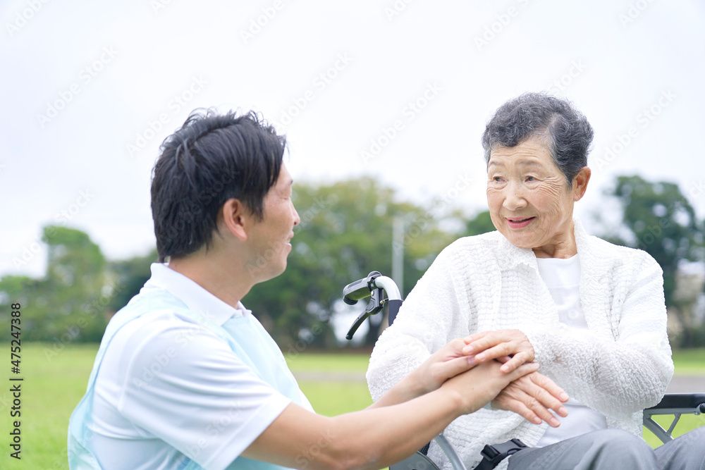 介護士と車椅子に乗る高齢者　屋外